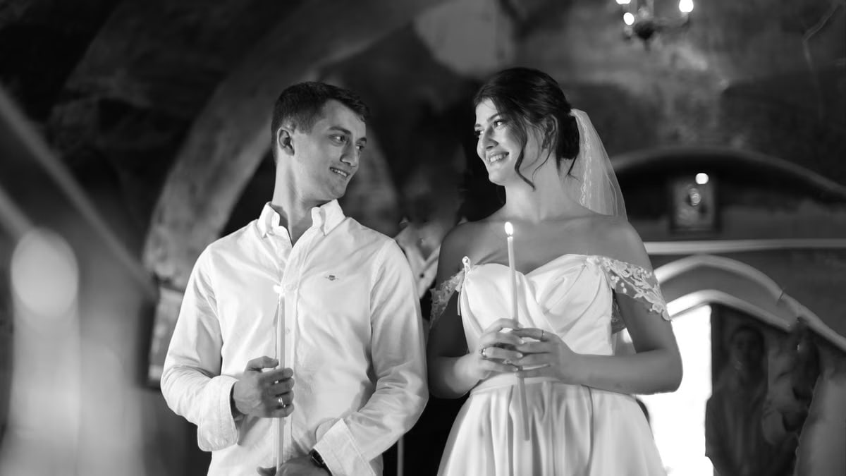A bride and groom holding candles in a traditional romantic wedding ceremony setting.